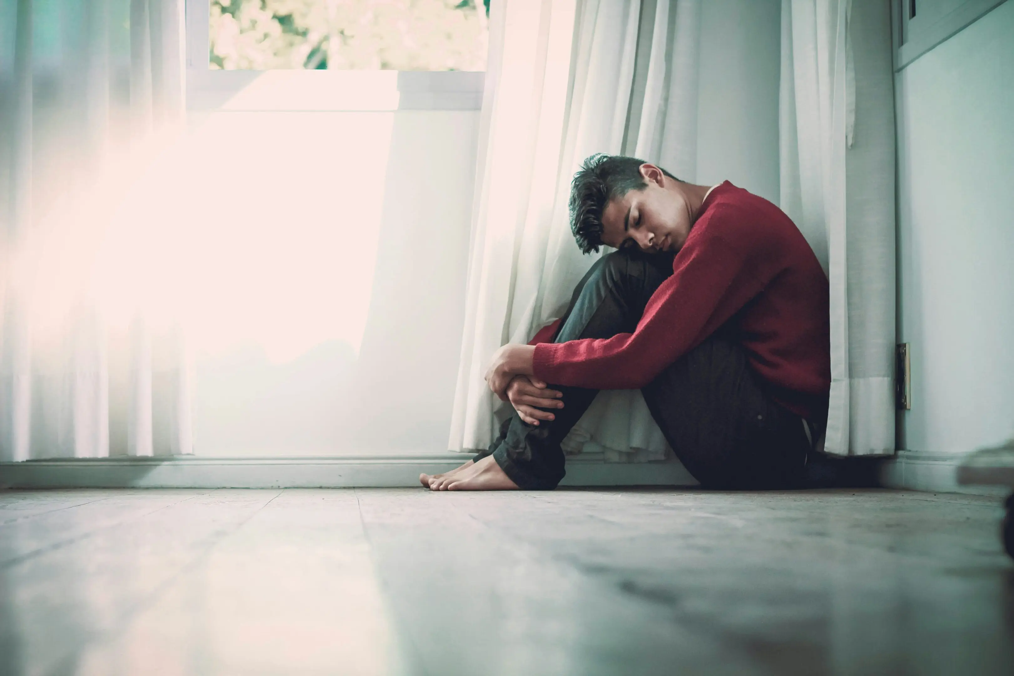Person sitting on floor by window.